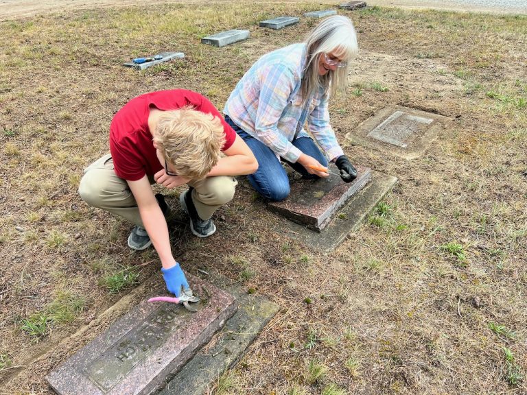 Two volunteers cleaning a grave marker